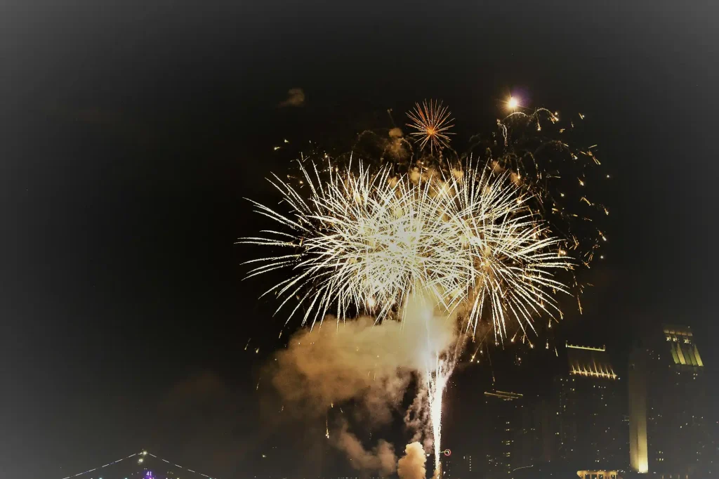 A stunning display of golden fireworks lighting up the night sky over a cityscape, celebrating New Year’s Eve.