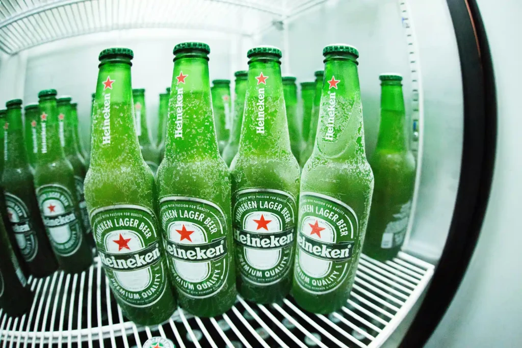 Chilled bottles of Heineken Lager Beer in a refrigerator, covered in frost, representing premium quality and ultimate refreshment.